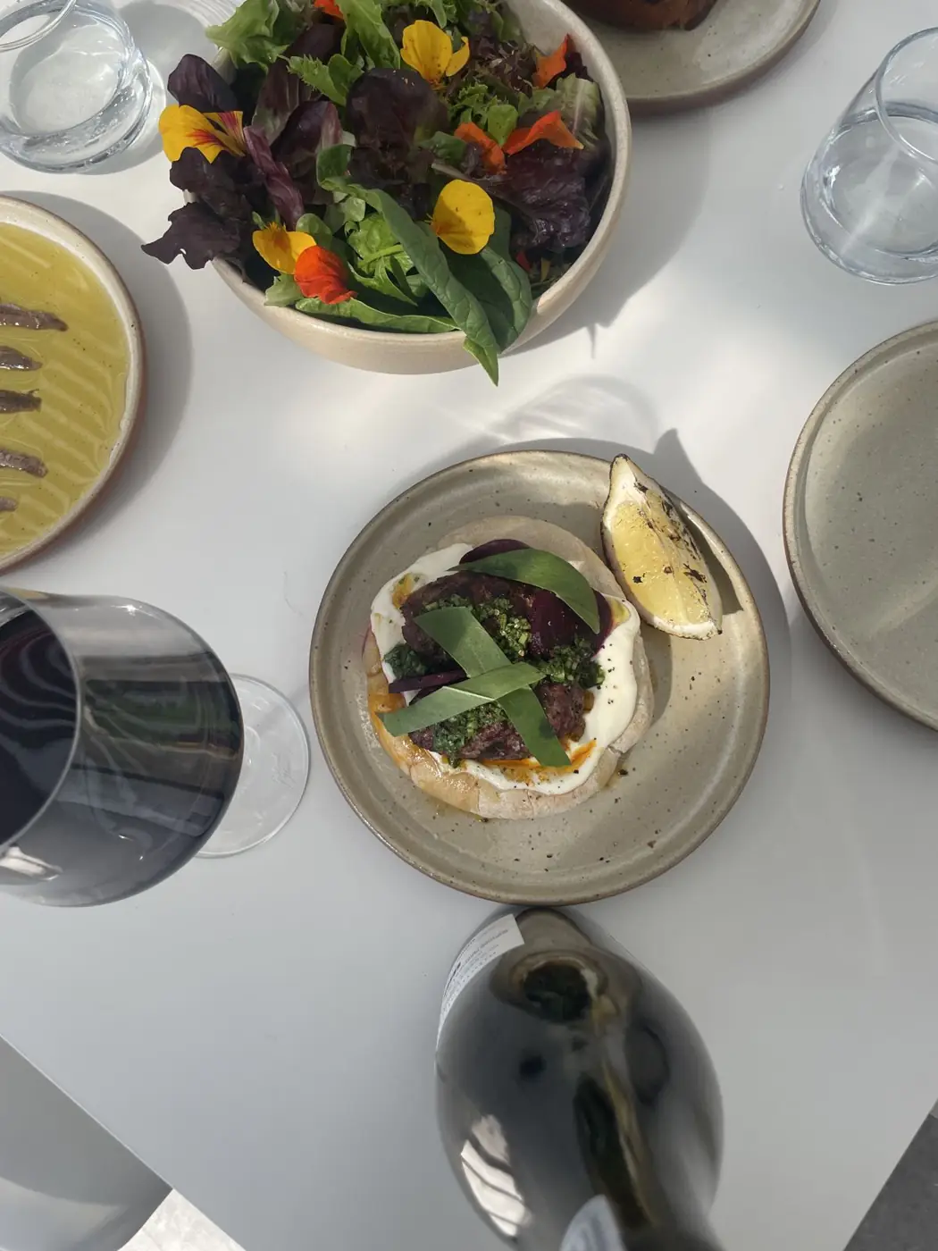 A shared table at Atrás: salad with flowers, flatbread and red wine