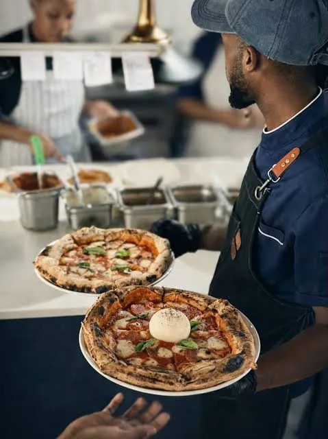 Two wood-fired pizzas carried out from the kitchen