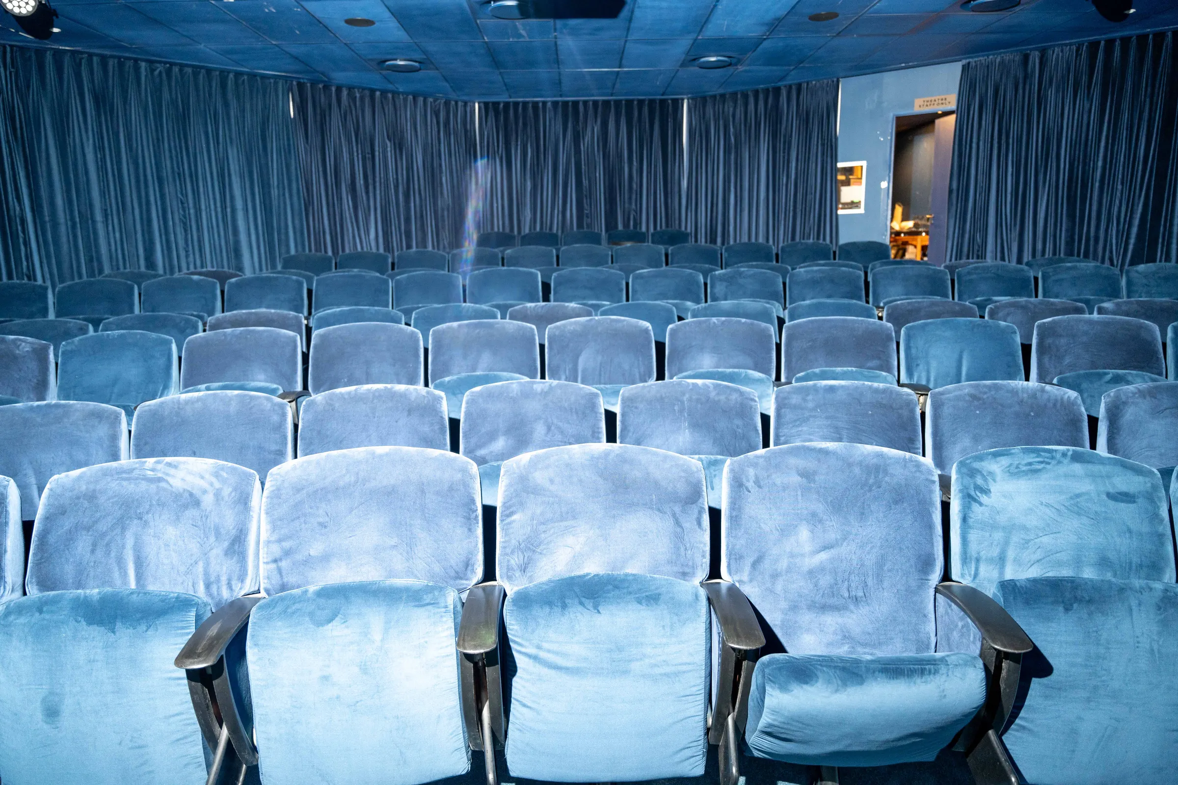 An empty BlackBrick cinema with blue velvet seats facing the screen